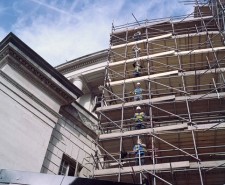 Scaffolders drop a pole between them on levels of scaffolding around Central Library