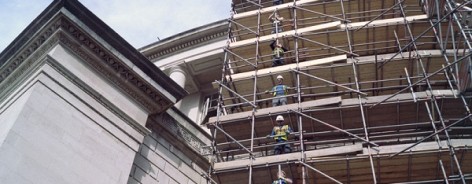 Scaffolders drop a pole between them on levels of scaffolding around Central Library