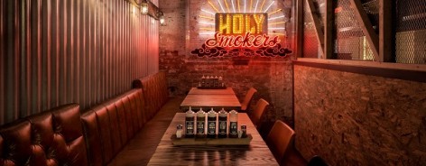 Interior shot of Red's True Barbeque with a long table and Holy Smoke neon sign