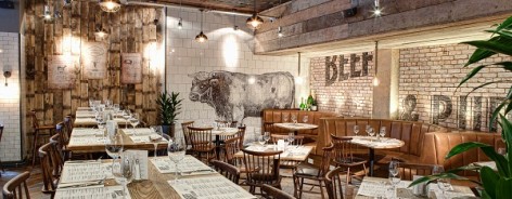 Photograph of Beef and Pudding's interior, with a bull printed on white tiles on the back wall