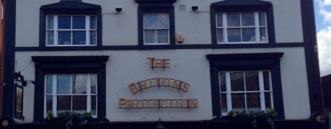 Photograph of the pub's frontage, with black framed windows.