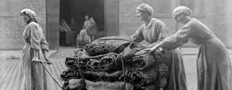 Black and white photo of women pushing a wooden trolley