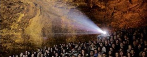 Photo of a crowd of people watching a film in a cave