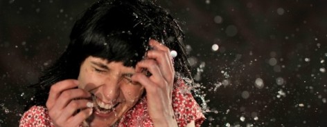 Photo of a girl in a pink top having water splashed in her face.