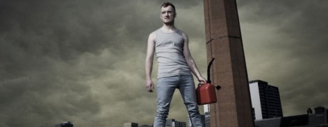 Photo of a man holding a petrol can against a clouded sky