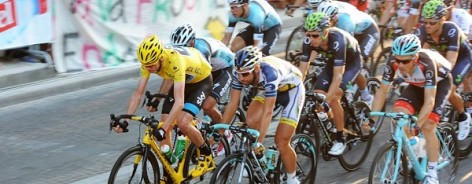 Photo of cyclists on the Tour de France, a man in front with a yellow helmet and jersey