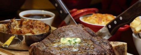 Photo of a steak with chive butter on a wooden board