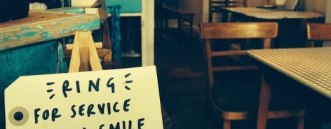 Photo of a handwritten label in a cafe that says "Ring for service with a smile"