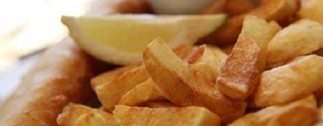 Photo of a plate of chips with battered fish and mushy peas
