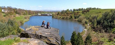 Photo of two women on a rock over looking a lake with their cameras