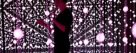 Photo of a woman walking in a purple dangling light sculpture