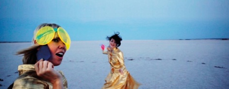 Photo of two wmoen wearing gold on a beach