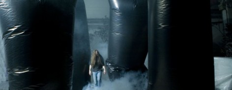 Long haired man amongs snow and black plastic sculptures