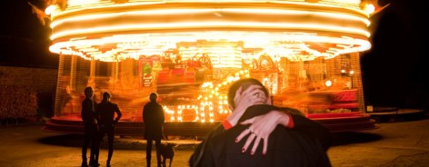 Photo of a couple kissing in front of a carousel
