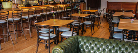 Photo of wooden tables and a green leather sofa