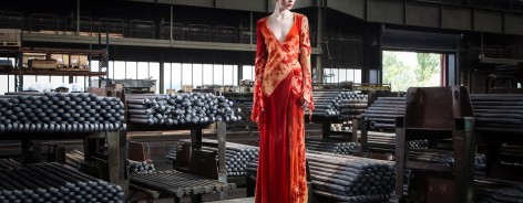A woman in a red dress stands in a warehouse