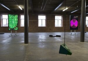 Photo of Erika Vogt's exhibition at The Calder; hanging machine parts in an industrial space