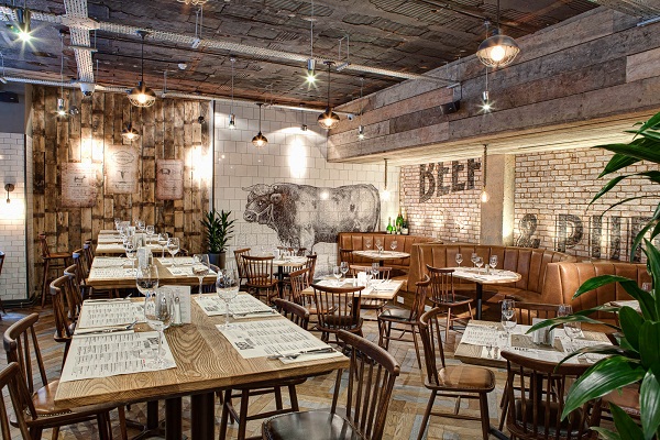 Photograph of Beef and Pudding's interior, with a bull printed on white tiles on the back wall