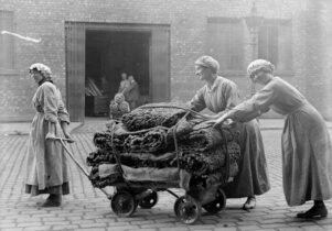 Black and white photo of women pushing a wooden trolley