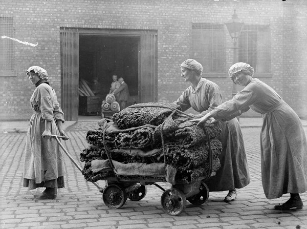 Black and white photo of women pushing a wooden trolley