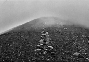 Black and white image of a Richard Long art piece; stones leading into mist.