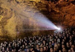 Photo of a crowd of people watching a film in a cave