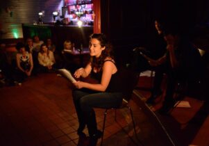 A woman reads from the page at the spring scratch night