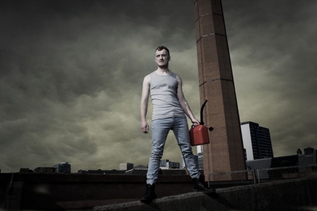 Photo of a man holding a petrol can against a clouded sky
