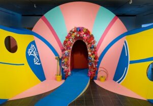 Photo of a Heather Phillipson installation, a walkway through a brightly coloured and suggestively shaped archway