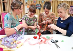 Photo of four women working with materials at a craft table