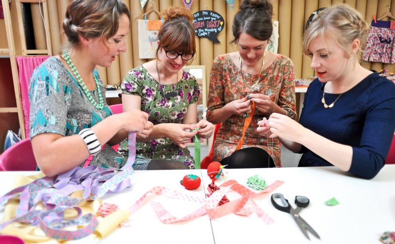 Photo of four women working with materials at a craft table