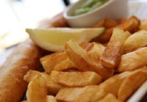 Photo of a plate of chips with battered fish and mushy peas