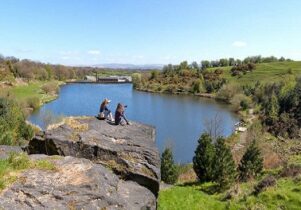 Photo of two women on a rock over looking a lake with their cameras