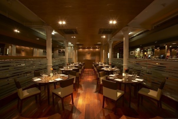 Photo of the restaurant interior, with wood floors and dark tables