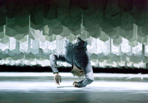 Photo of Akram Khan hanging upside down amid a maze of paper