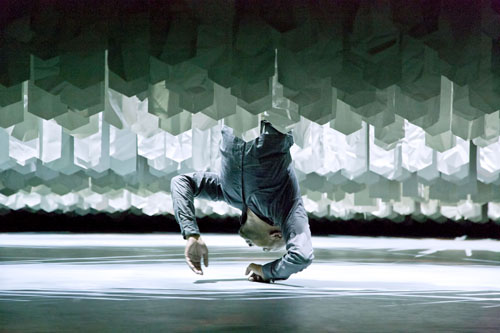 Photo of Akram Khan hanging upside down amid a maze of paper