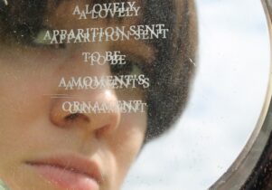 Photo of a mirror inscribed with words, with a woman's reflection in it