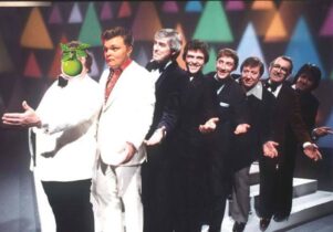 Photo of comedian Rob Pickford in a line of men in a while suit