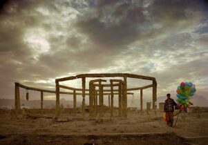 The round ruins of a former teahouse, with a man in front holding colourful balloons