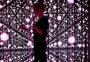 Photo of a woman walking in a purple dangling light sculpture