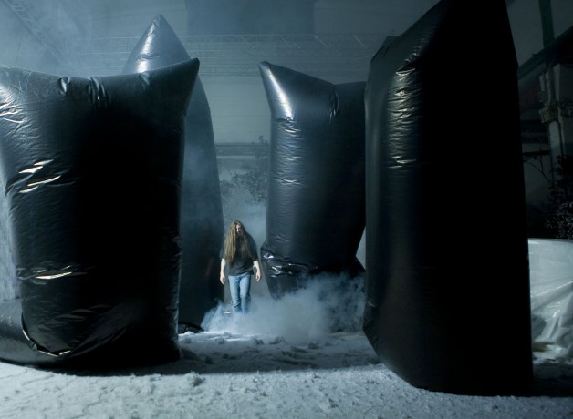 Long haired man amongs snow and black plastic sculptures