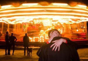 Photo of a couple kissing in front of a carousel