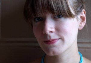 Head shot of Laura, wearing a turquoise necklace