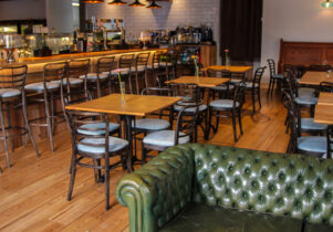 Photo of wooden tables and a green leather sofa