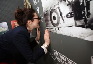 A woman looks in at a peephole of an aerial photo