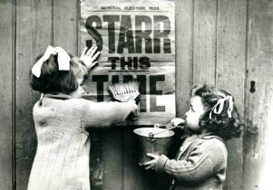 Black and white photo of two girls with poster