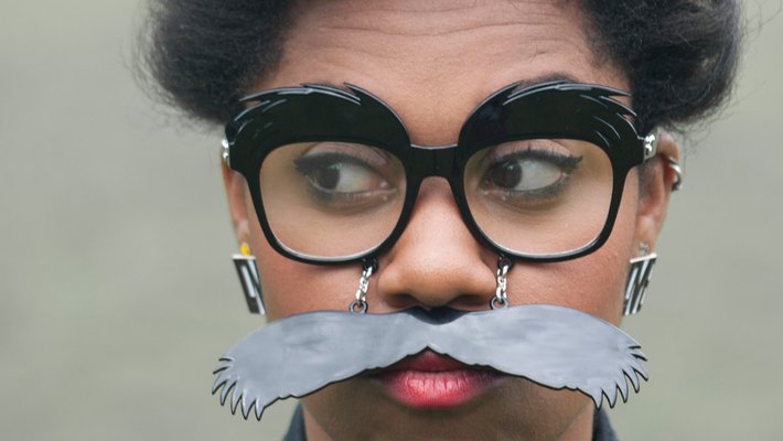Woman wears glasses and a fake moustache