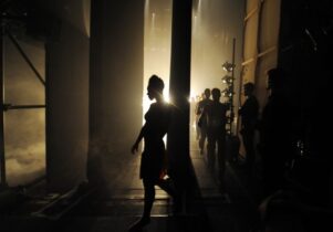 Dark photo of dancers behind stage