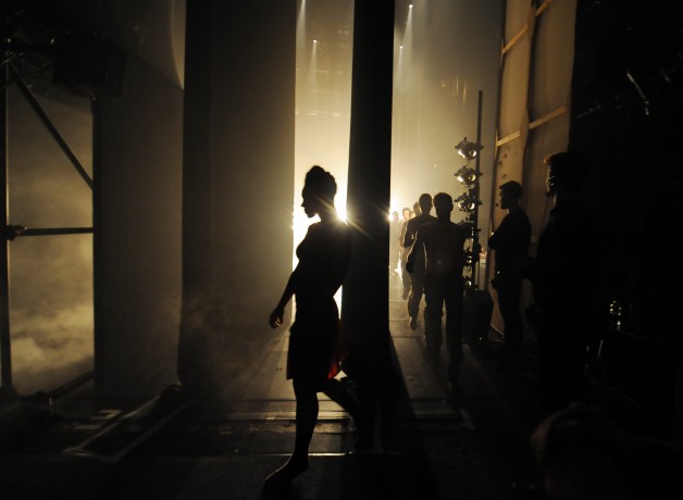 Dark photo of dancers behind stage