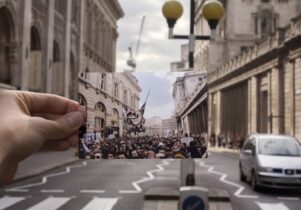 Someone holds a photograph of a once crowded, now empty street.